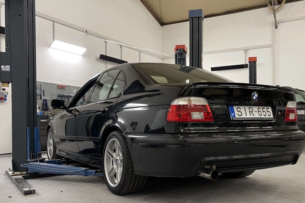 Fekete BMW 5-ös emelőn a Q-Service műhelyben